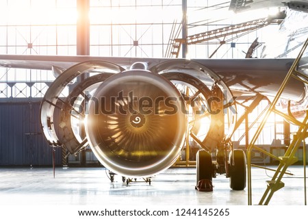 Opened hood airplane engine jet under maintenance in the hangar ,with bright light flare at the gate Royalty-Free Stock Photo #1244145265