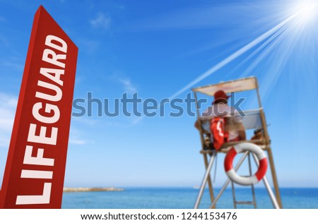Lifeguard station with a red signboard, surveillance tower, lifebuoy, sky and sun rays