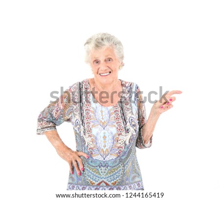 Happy old woman smiling while pointing her finger to one side against a white background