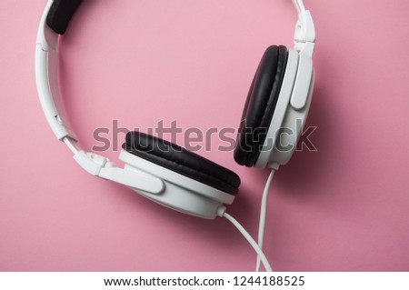 closeup of white headphones on pink background