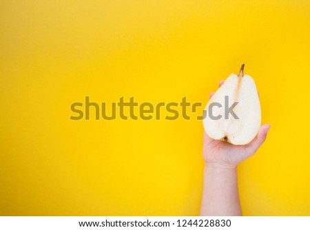 Two yellow sweet and ripe pears in hchild's hand on a yellow background. Minimal food concept.