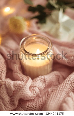 Cozy decor. A cup of cappuccino. Candle in a glass jar, pink knitted blanket, rose, laptop. Cozy. Autumn.