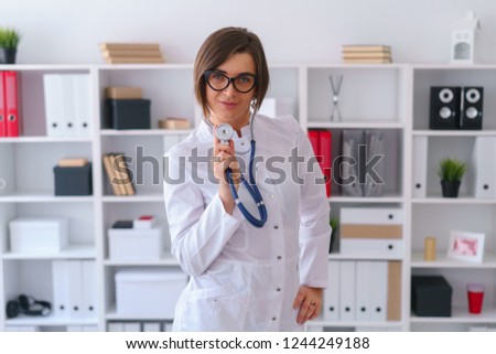 young beautiful doctor in white gown stay in her consulting room wait for patients love her job concept