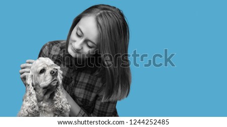 Black and white image of an american cocker spaniel and young beautiful woman on blue background with copy-space