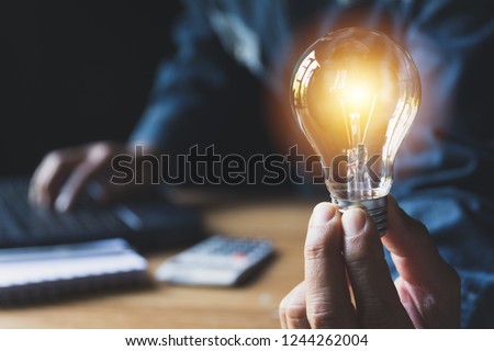Hand of male holding a light bulb for accounting and creative concept. Royalty-Free Stock Photo #1244262004