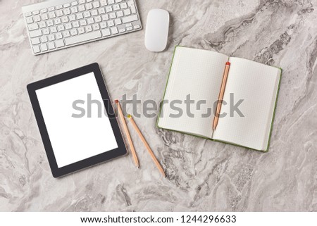 Technological tool tablet and phone on the grey marble with keyboard mouse notebook vase of plant and pencil.