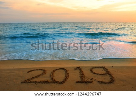 Happy new year concept, 2019 written in the sand on a beach, during sunset hour.