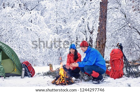 Camping in the winter forest of a couple in love. Royalty-Free Stock Photo #1244297746