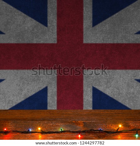 Festive grunge background with Christmas lights on a wooden surface and England flag
