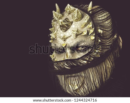 Monster with white eyes and thorns. Alien with dragon skin and grey beard. Horror and mystery concept. Man with fictional makeup. Demon hiding face with scarf isolated on black, copy space
