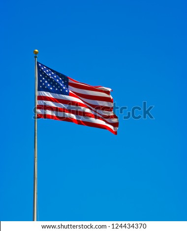 American flag waving in the wind against a blue sky ina sunny day