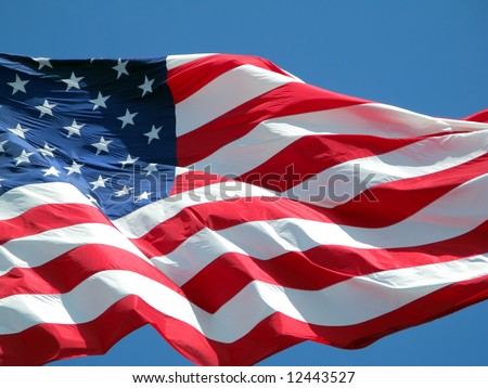 Waving American flag against a blue sky background.