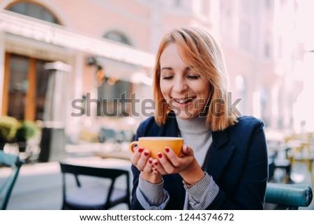 Photo of positive dark skinned mixed race female ejoys good rest at coffee shop, drinks hot beverage, happy to discuss something funny with friends. People, leisure and eating concept