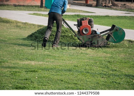 A Person cutting grass from a machine 