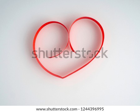 Red ribbon heart-shaped on a white background. Space for design