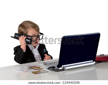 One small little girl (boy) calling phone, wearing black suit and glasses. Computer, credit cards are on table. Business concept. Isolated object.