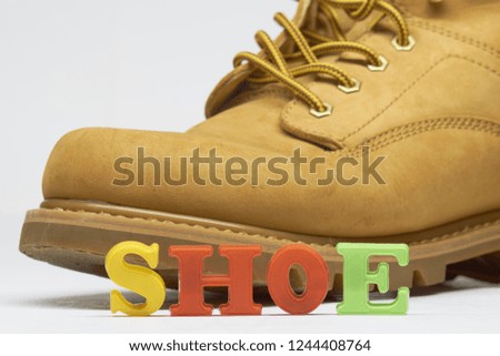 The word "shoe", laid out in colored letters, is illustrated with a real yellow leather shoe. Education project.                           