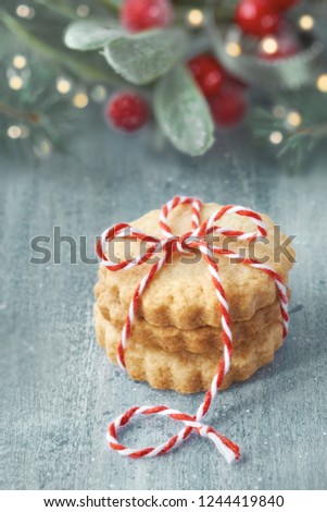 Stack of butter cookies tied with checkered cord on green and red festive background with Christmas decorations