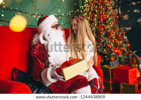 Little girl sitting with santa and presents on Christmas
