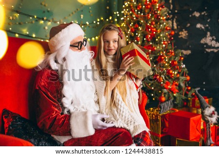Little girl sitting with santa and presents on Christmas