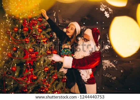 Santa with little girl decorating christmas tree together