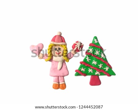 Pretty girl holding the pink heart and red gift box and cute Christmas tree made from plasticine clay placed on white background, cute child dough wearing a coat in winter festival