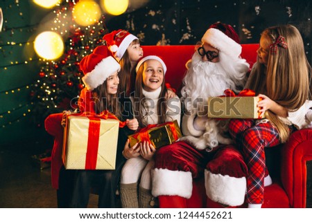 Group of kids sitting with santa and presents on christmas eve