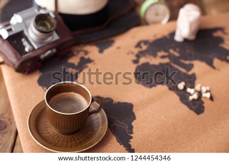 A cup of aromatic coffee on the map and accessories for travel. Vintage photo. Tourism and holidays. Free space for text. Top view