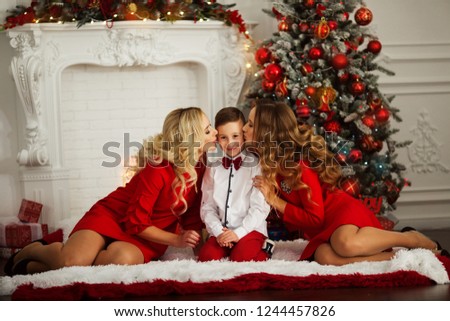 Beautiful family mom, daughter and son are sitting near xmas decorated tree