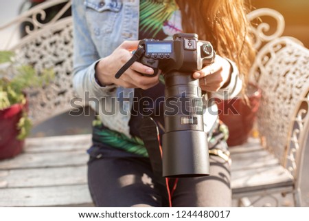 Close-up of professional female photographer on the street photographing on a camera.