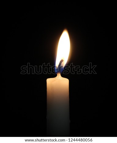 A close-up photograph of a single burning candle in front of a black background. This photo was taken in Brisbane, Australia. 
