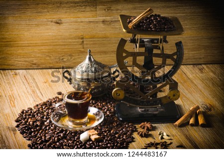 Vintage mailing scales with coffee beans, cup of coffee, sugar cup on wooden background.