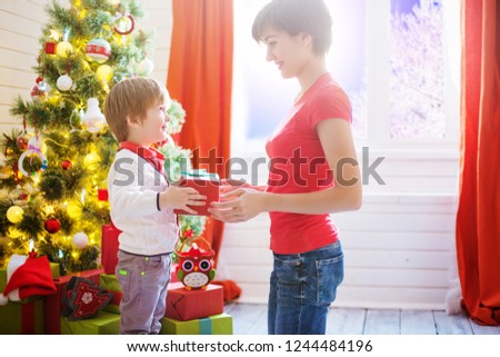 Mother gives a gift to her son for Christmas or son gives a gift to his Mom. Gift beautiful box in hand close.
