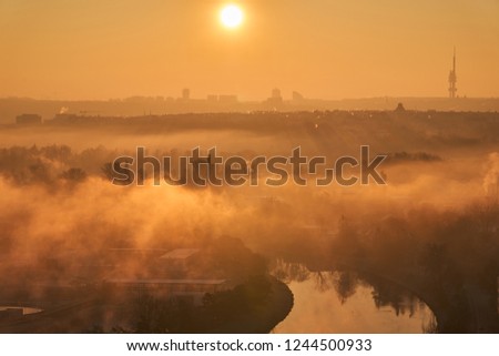  Cityscape Picture of Prague, capitol of Czech Republic taken in the morning during the sunrise in golden hour. Vltava river with fog, smog or mist over the water.                              