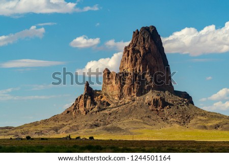 Agathla Peak (also called El Capitan Peak) just north of Kayenta Arizona in Monument Valley during sumer time with a blue sky and some clouds