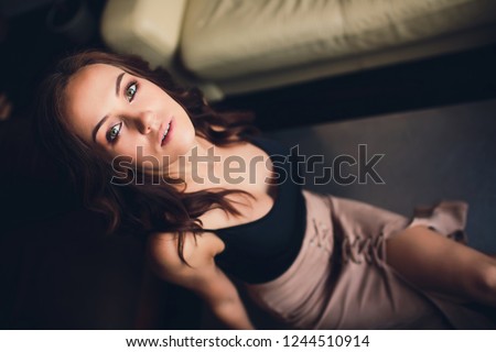 fashion interior photo of beautiful woman with dark hair in elegant gold dress lying on silver table.