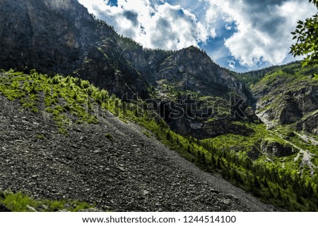 Beautiful views and landscape of Altai nature. The majestic landscape of high mountains and cliffs against a blue sky with clouds on a sunny day.