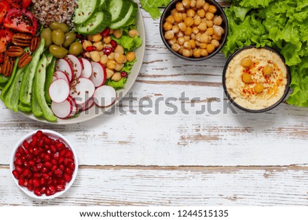Vegan buddha bowl. Bowl with fresh raw vegetables - cabbage, carrot, green pepper, lettuce salad, tomatoes cherry, nuts and pomegranate. Diet and healthy eating,top view,copy space,vegetable appetizer
