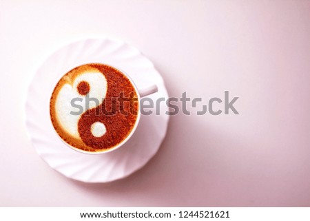 a cup of cappuccino coffee with a yin and yan cinnamon symbol pattern on milk foam