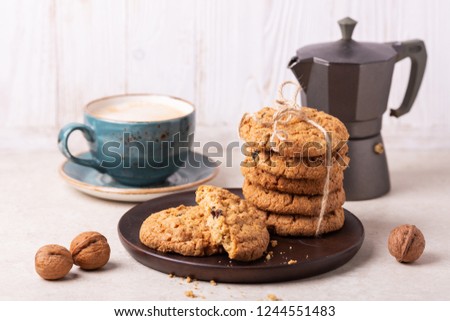 Cup of coffee, oatmeal cookies, coffee maker on white wooden background. Bright morning