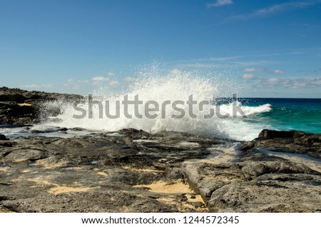 Adventure on the rocky coast near Playa de la Conchas beach on La Graciosa island, Canary Islands, Atlantic ocean, the strong waves are spreading over the rocks.