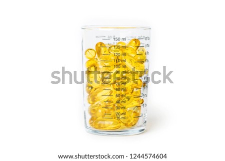 Bright yellow fish oil capsules in the glass measurement on white background shot with studio light