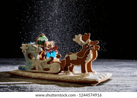 Christmas gingerbread sleigh with deers on a dark background with falling snow.