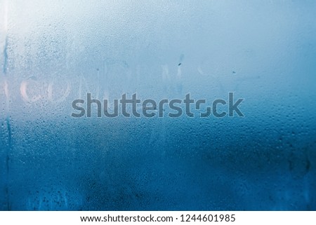 The inscription condenses on glass close-up with condensation. Background with water drops. High humidity indoor