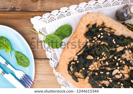 Traditional pie with spinach and nuts. Tasty homemade pastry on wooden background. Photo in the style of rustic. Fresh green vegetables. Italian food. Free space to copy text