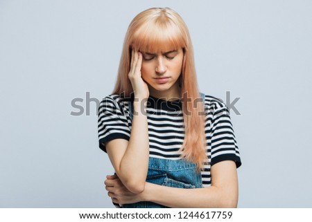 Tiredness, headache, overwork concept. Portrait of 
attractive tired stressful woman has a headache, feeling pressure, tries to concentrate, gather with thoughts, keep hand on temple, closed eyes.