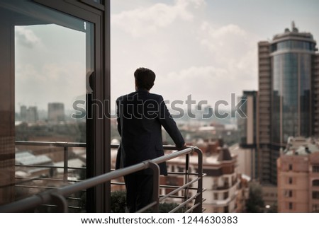 Take a pause. Full length back side portrait of businessman enjoying city view on office balcony. Copy space on right