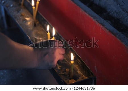 Buddhists make merit,Placing a lighted candle and lit incense with candles frame on the altar of Buddha  at temple.  Selective focus.