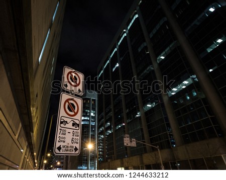 Typical North American parking and no parking signs with detailed instructions on the regulations taken at night in Ottawa CBD, Ontario, Canada, with a sign indicating bus lanes behind

