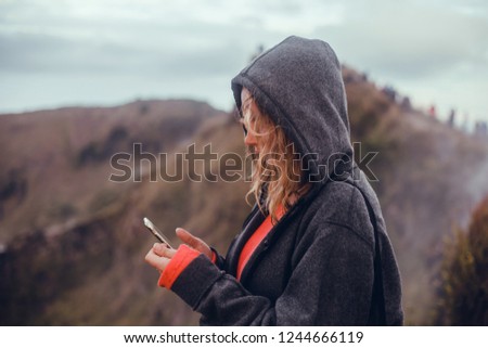 Woman using smartphone in hand, volcano, Bali,girls traveler looking at volcano Rinjani, island Lombok. Indonesia.Young backpacker traveling along mountains, happy female walking discovering world, 